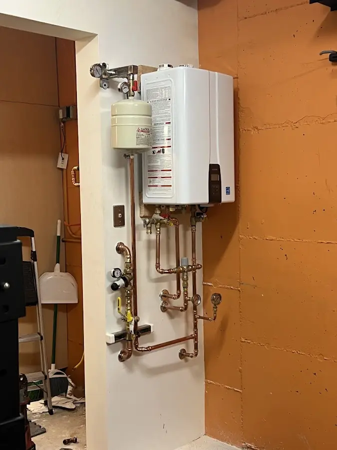 Plumbing technician inspecting water heater connections in Enon